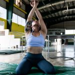 Focused gymnast in a sports hall performing exercises on a mat.